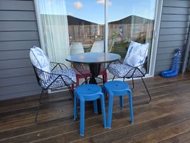 A table with chairs and stools on an outdoor patio at Serendipity - One Tree Point Holiday Home One Tree Point