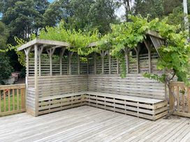 A wooden seating area with a pergola and vines at Whangarei Retreat - Whangarei