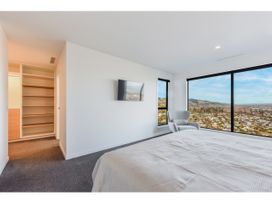A bedroom with a bed, armchair, television and window view at Horizon View Retreat - Nelson Holiday Home in Nelson