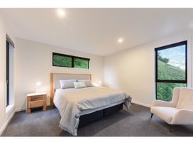A bedroom with a bed and an armchair at Horizon View Retreat - Nelson Holiday Home Nelson