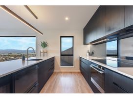 A kitchen with windows and dark cabinets at Horizon View Retreat - Nelson Holiday Home