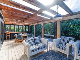 A conservatory with seating and dining area at Living The Dream - Matarangi Holiday Home, Matarangi