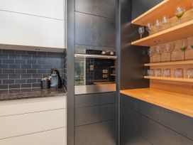 A kitchen with cabinets, an oven, and glassware at Living The Dream - Matarangi Holiday Home, Matarangi
