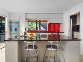 A kitchen with an island and stools at Living The Dream - Matarangi Holiday Home Matarangi