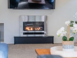 A living room with a fireplace and television at Living The Dream - Matarangi Holiday Home Matarangi