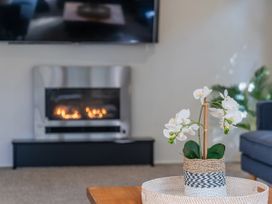 A living room with a fireplace and a plant on the coffee table at Living The Dream - Matarangi Holiday Home in Matarangi