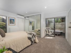 A bedroom with a bed and a mirror at Living The Dream - Matarangi Holiday Home, Matarangi