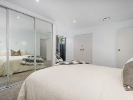 A bedroom with a bed and mirrored closet at Living The Dream - Matarangi Holiday Home, Matarangi