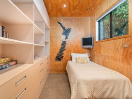 A bedroom with a single bed and bookshelf at Living The Dream - Matarangi Holiday Home Matarangi