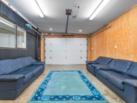 A garage with sofas and a carpet at Living The Dream - Matarangi Holiday Home in Matarangi