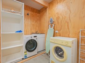 A laundry room with washing machine, dryer, and sink at Living The Dream - Matarangi Holiday Home, Matarangi