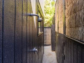 An outdoor shower area with wooden walls and a window at Living The Dream - Matarangi Holiday Home, Matarangi