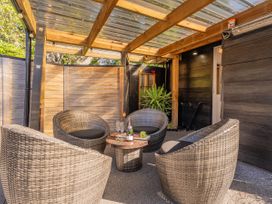 An outdoor patio with wicker chairs and a table at Living The Dream - Matarangi Holiday Home Matarangi