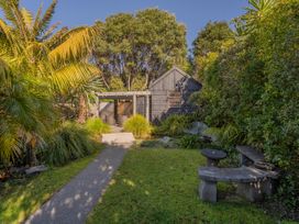 A garden with a pathway and a bench at Living The Dream - Matarangi Holiday Home, Matarangi