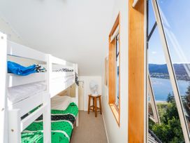 A bedroom with a bunk bed and a fan at The Bach - Tairua Holiday Home Tairua
