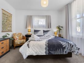 A bedroom with a bed, chair, and plant at Ohakune Holiday Home in Ohakune