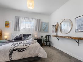 A bedroom with a bed, shelf, and artwork at Ohakune Holiday Home in Ohakune