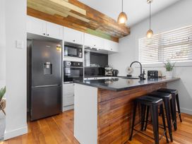 A kitchen with appliances and bar stools at Ohakune Holiday Home in Ohakune
