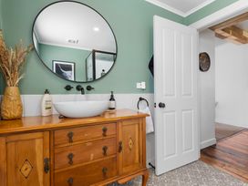 A bathroom with a vanity and a round mirror at Ohakune Holiday Home in Ohakune
