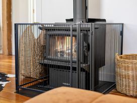 A wood stove within a guard and baskets in the living room at Ohakune Holiday Home Ohakune