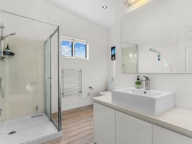 A bathroom with a shower stall, toilet, and sink at Mangawhai Heads Holiday Home in Mangawhai Heads