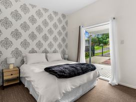 A bedroom with a bed and a sliding door leading to a patio at Mangawhai Heads Holiday Home Mangawhai Heads