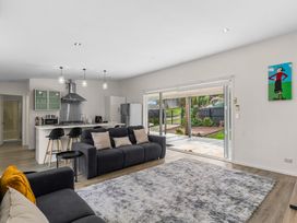A living room with a sofa and kitchen at Mangawhai Heads Holiday Home Mangawhai Heads