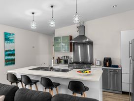 A kitchen with island, stools, and appliances at Mangawhai Heads Holiday Home in Mangawhai Heads