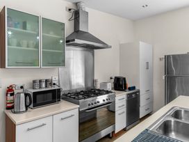 A kitchen with a stove, oven, and microwave at Mangawhai Heads Holiday Home in Mangawhai Heads
