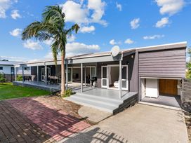 An outdoor view of a house with a deck and palm tree at Mangawhai Heads Holiday Home Mangawhai Heads