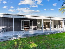 A house with a deck and chairs at Mangawhai Heads Holiday Home in Mangawhai Heads
