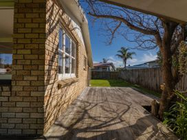 A wooden deck and a brick wall of a house at They Carolyn - Whangamata Holiday Home Whangamata