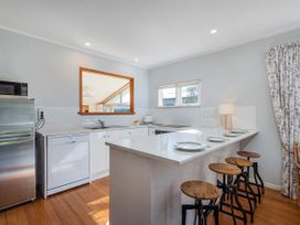 A kitchen with a counter and stools at They Carolyn - Whangamata Holiday Home in Whangamata