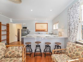 A kitchen with bar stools and a refrigerator at They Carolyn - Whangamata Holiday Home in Whangamata