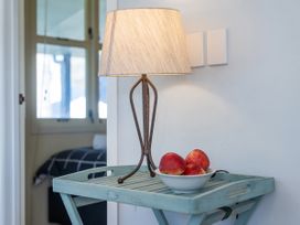 A table with a lamp and a bowl of apples at They Carolyn - Whangamata Holiday Home, Whangamata