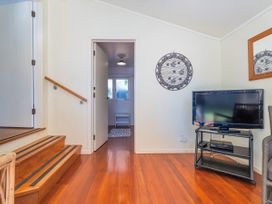 A living room with stairs and a television at They Carolyn - Whangamata Holiday Home, Whangamata