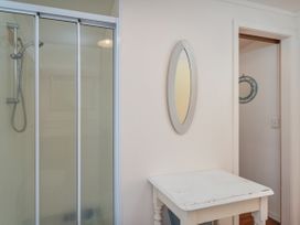 A bathroom with a shower, mirror, and a table at They Carolyn - Whangamata Holiday Home in Whangamata