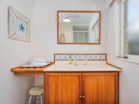 A bathroom with a mirror and sink at They Carolyn - Whangamata Holiday Home, Whangamata