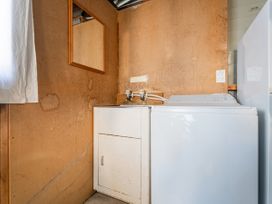 A laundry room with a sink and washing machine at They Carolyn - Whangamata Holiday Home, Whangamata