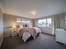 A bedroom with a bed, bedside lamp and window at Te Anau