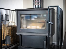A wood stove with a fire screen in a living room at Te Anau