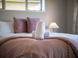 A bed with pillows and towels at Te Anau 