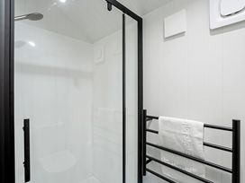 A shower with glass door and towel rack at Apres Peak - Queenstown Holiday Home in Queenstown