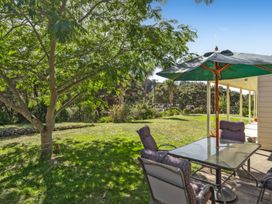 A garden with a table and chairs under an umbrella at Hill Cottage - Featherston Holiday Home, Featherston