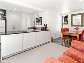 A kitchen with cabinets, refrigerator, and table at Hill Cottage - Featherston Holiday Home, Featherston