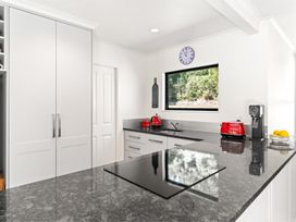 A kitchen with cabinets, sink, stovetop, and appliances at Hill Cottage - Featherston Holiday Home, Featherston