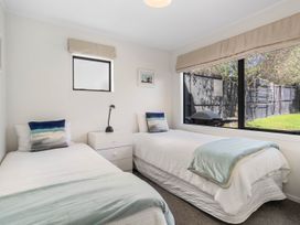 A bedroom with two beds and a lamp at Waihi Beach Holiday Home in Waihi Beach