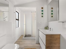 A bathroom with a sink, toilet, and shower at Waihi Beach Holiday Home in Waihi Beach