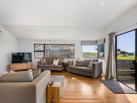 A living room with a television and two sofas at Waihi Beach Holiday Home in Waihi Beach