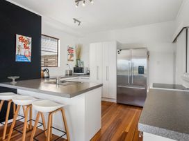 A kitchen with a fridge and bar stools at Waihi Beach Holiday Home in Waihi Beach